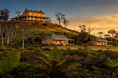 Read: Illaroo - Dharawal and Dhurga Country by Megan Cartwright, Hawker College Image: A homestead on the hill, with smaller cottages below in the Australian bush. It's sunset. There are gum trees and ferns. This image was created using AI Tools.